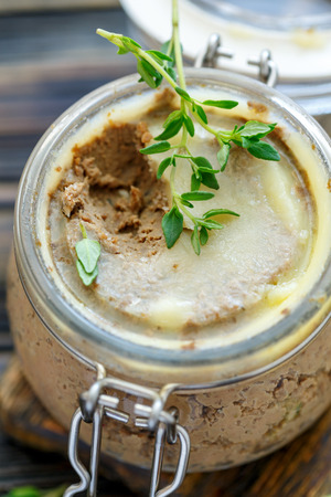 Glass jar with beef liver pate filled with melted butter close-up.の写真素材