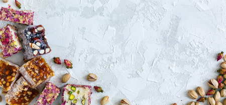 Mixture of oriental sweets rahat lukum, pistachios and small roses on a white concrete background. View from the top.の写真素材