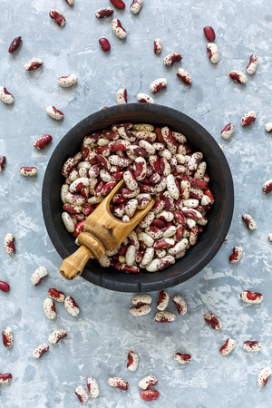 Old wooden bowl with colorful beans on grey concrete background. View from the top.の写真素材
