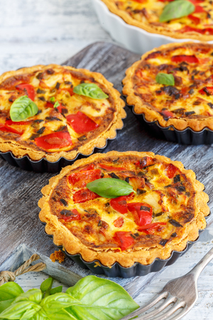 Homemade mini quiche with chicken, green onions and sweet pepper on an old wooden table.の写真素材