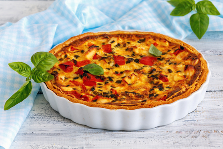 Ceramic mold with savory chicken pie, green onion and sweet pepper on white wooden table.の写真素材