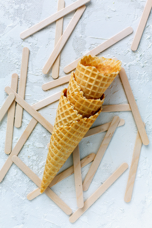 Waffle cones and sticks for ice cream on white concrete background.Top view.の写真素材