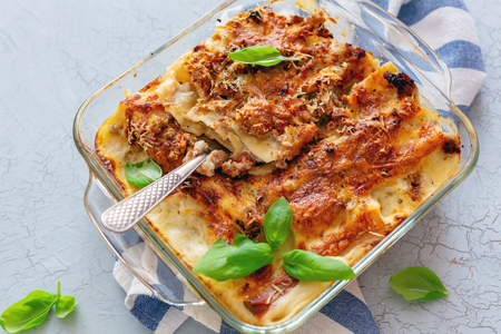 Cannelloni with minced meat and cream sauce in a glass pan on a linen cloth. Top view.の写真素材