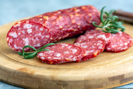 Cutting board with slices of salami and rosemary close-up, selective focus.の写真素材