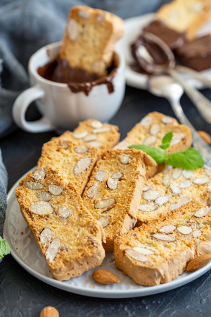 Plate with slices biscuit cookies with almonds on a dark textured background, selective focus.の写真素材