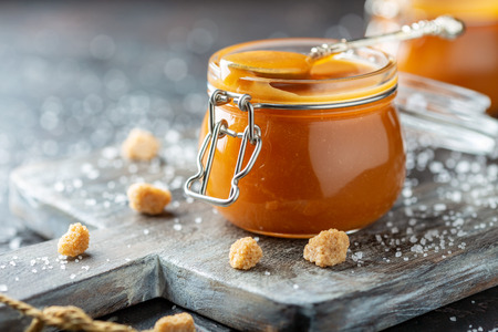 Homemade caramel with sea salt, pieces of cane sugar and salt crystals on an old wooden serving board, selective focus.の写真素材