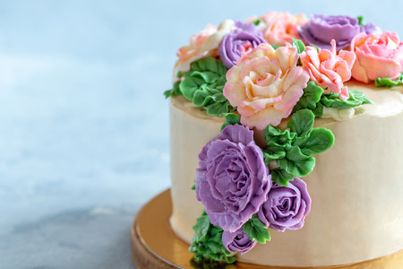 Delicious cake with buttercream roses close-up on a light blue background, selective focus.の写真素材