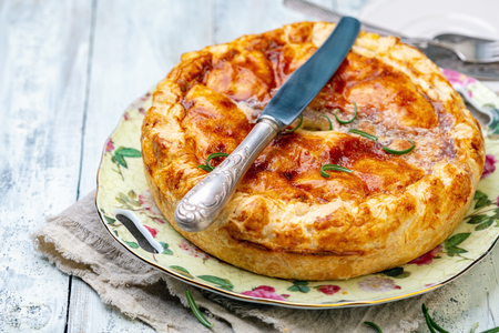 Plate with a traditional French closed pie with potatoes and rosemary on an old wooden table, selective focus.の写真素材