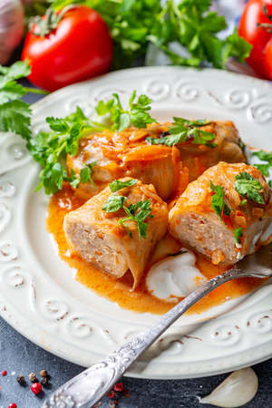 Cabbage rolls with minced meat served on a white plate on an old rustic table with sour cream, selective focus.の写真素材