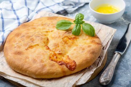 Homemade closed cheese pie on wooden serving board, selective focus. Traditional Georgian cuisine.の写真素材