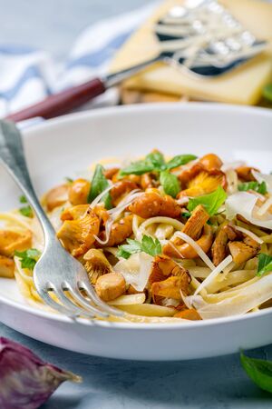 Linguine with wild chanterelles, parmesan, parsley and green basil in a white plate on linen cloth, selective focus.の写真素材