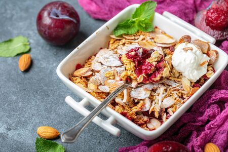 Plum cake with crumb and oatmeal crisp in a white pot served with thick natural yoghurt, selective focus.の写真素材