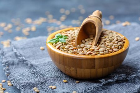 Brown lentils vegetarian food in a wooden bowl on linen homespun, selective focus.の写真素材