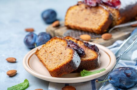 Plate with slices of homemade plum cake with almonds and spicy plum on a gray textured background, selective focus.の写真素材