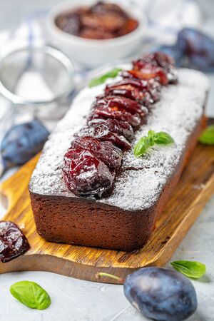 Delicious plum cake with spicy plums on a wooden serving board close-up, selective focus.の写真素材