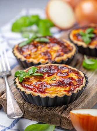 Traditional onion mini pies with cream filling on old wooden serving board, selective focus.の写真素材