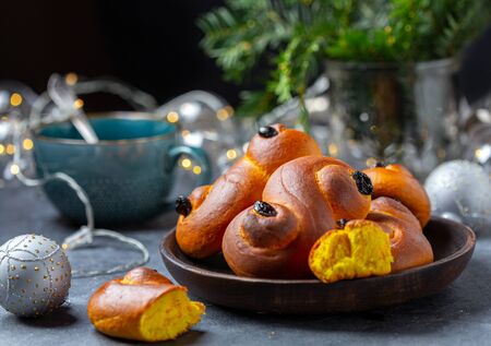 Swedish Christmas traditions.Saffron raisin buns on a dark table with a Christmas garland, selective focus.の写真素材