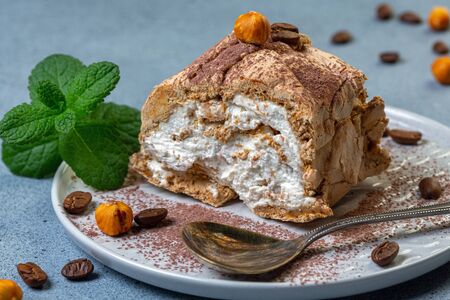 Piece homemade of meringue-coffee roulade served with a sprig of mint on a plate, selective focus.の写真素材