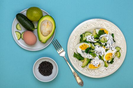 Healthy salad of green vegetables-spinach, avocado, cucumbers and egg with yogurt and lime sauce is...