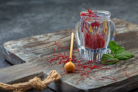 Precious Oriental spice saffron in a glass vial on a wooden board with copy of the space, selective focus.の写真素材