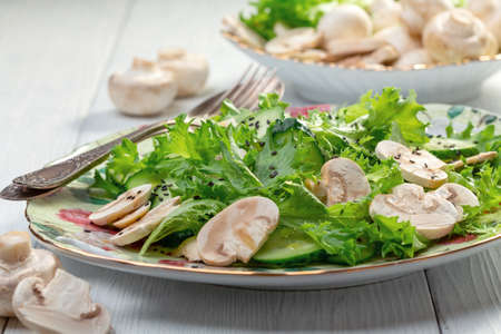 Vitamin salad of cucumbers, green salad and raw mushrooms served in a large dish, selective focus.の写真素材
