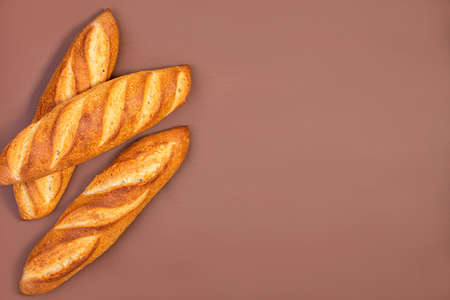 Freshly baked traditional baguettes and a bread knife on a contrasting two-color background with a...