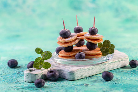 Delicious tiny pancakes and fresh blueberries on skewers. New food trend concept.の写真素材