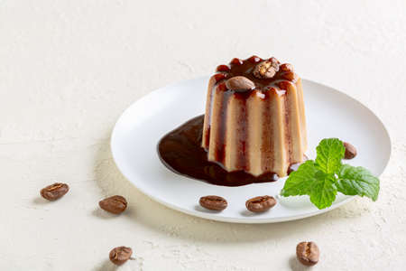 Italian dessert panna cotta with chocolate sauce and decorated with coffee beans is served on a...