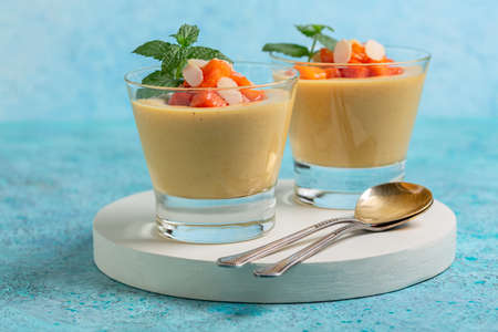 Delicate dessert of milk, cream and fresh peaches in dessert glasses, served with slices of fresh mint and peach on a slate stand, selective focus. copyspace.の写真素材