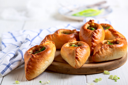 Traditional small pies with spicy meat filling on a wooden serving board close-up, selective focus. Concept of traditional Russian baking.の写真素材