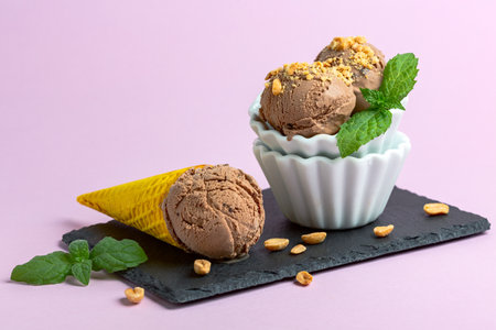 Vase and a waffle cone with homemade chocolate ice cream sprinkled with peanuts served with a sprig...