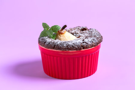 Chocolate muffin with pear and sprig of mint in a ceramic bowl, selective focus. Copy space.の写真素材