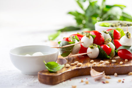 Caprese salad on skewers with fresh mozzarella, cherry tomatoes and basil on a wooden serving board, selective focus.の写真素材