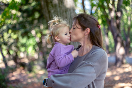 Loving mother kisses her young daughter, showcasing the bond between them amidst nature.の写真素材