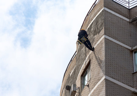 Worker repairing a building facade using rope access.の写真素材