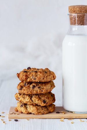 Crunchy homemade oatmeal cookies stacked with bottle of milk. Close up.