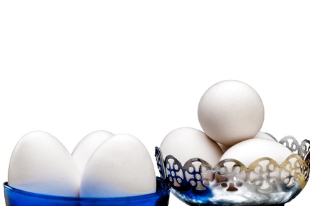 White eggs in glass bowl, basket, front lit, isolated, white background, copy space