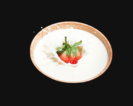 Strawberry milk into a cup of water distribution on a black background.の写真素材