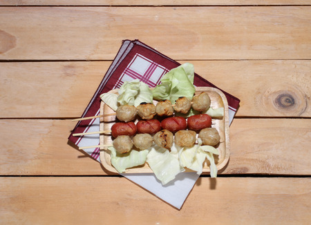 Meatballs in a wooden plate with green leaves on a wooden table.の写真素材