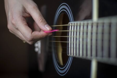 Fingers forming a chord on a guitar fingerboard. Male hands playing on guitar. Selective focus