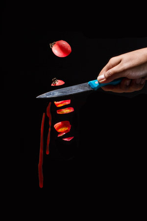 The man with a knife cut tomatoes into pieces in the darkの写真素材