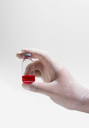 A hand with a glove holding a test tube with bloodの写真素材