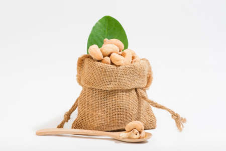 Cashews as a snack Snacks placed in sacks and placed on a wooden spoon area, white background.