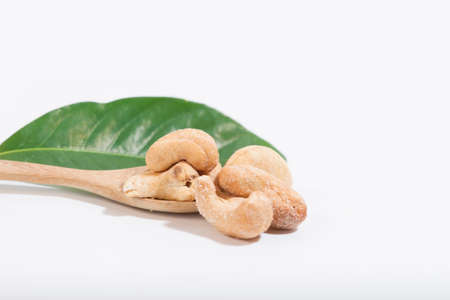 Cashews are a snack. appetizer and put on a wooden spoon white backgroundの写真素材