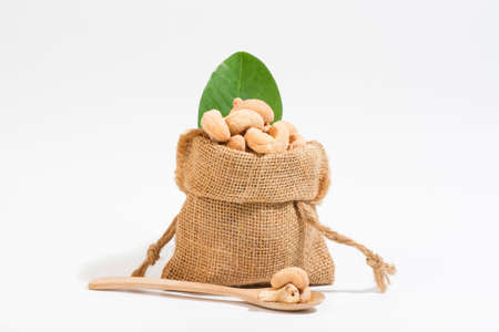 Cashews as a snack Snacks placed in sacks and placed on a wooden spoon area, white background.の写真素材