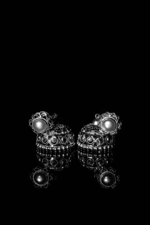 Earring Gold Jewelry Traditional With Stones and Two Golden earrings with reflection . Pair of golden earring with pearl tone on black background. Luxury female jewelry, close-upの写真素材