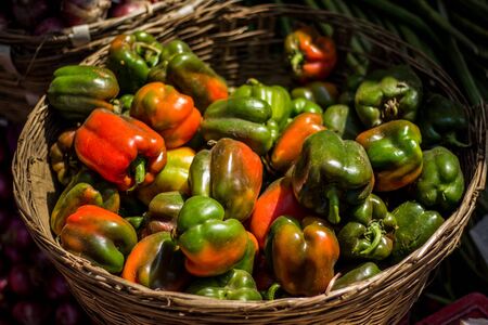 Selling capsicum wire basket vegetable bowl on street market. Mixed red and green capsicum for sale on vegetable basket.の写真素材