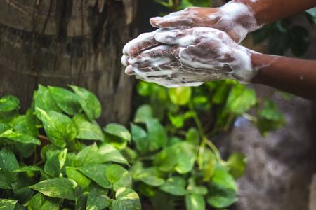 Washing hands.Man washing his hands in the garden at home. Wash hands with soap warm water and rubbing nails and fingers washing frequently. Hygiene & Cleaning Handsの写真素材