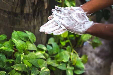 Washing hands.Man washing his hands in the garden at home. Wash hands with soap warm water and rubbing nails and fingers washing frequently. Hygiene & Cleaning Handsの写真素材