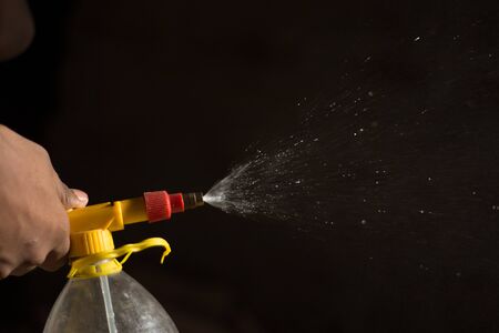 Air pump water spray bottle. close up of a spraying water drops isolated on black background.の写真素材